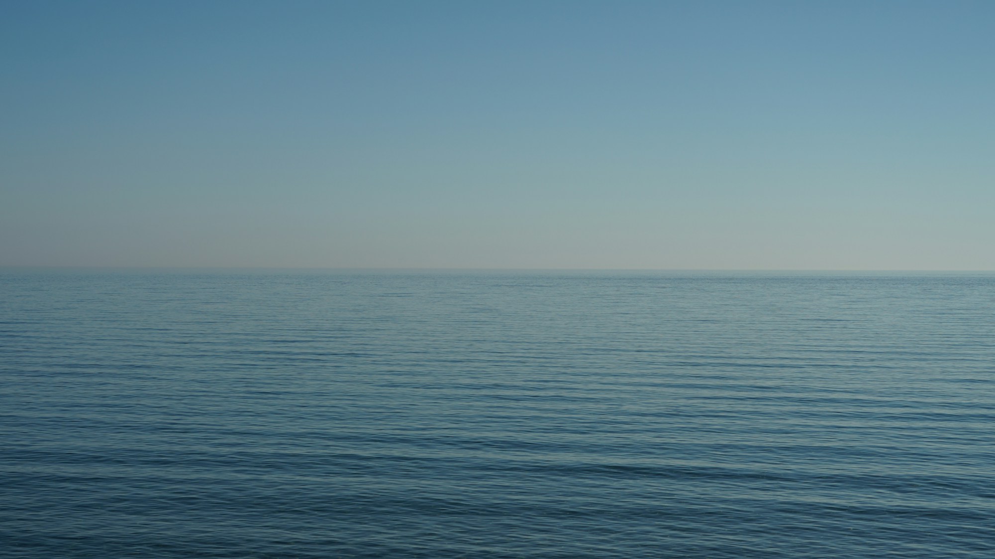 Quiet blue water meeting an open sky